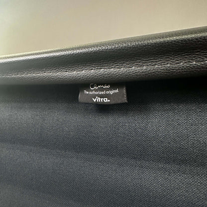Close-up of Vitra EA 119 black leather chair label showing authentic branding and high-quality material details