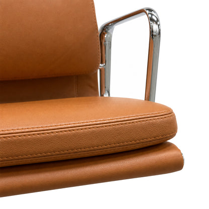 Vitra Eames Alu Chair EA 208 mit cognacfarbenem Premium-Lederpolster und glänzendem Chrom-Armlehnengestell.