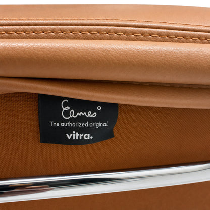 Detailaufnahme eines Vitra Eames EA 208 Stuhls mit cognacfarbenem Premium-Leder, Chromrahmen und Eames-Markenlabel.