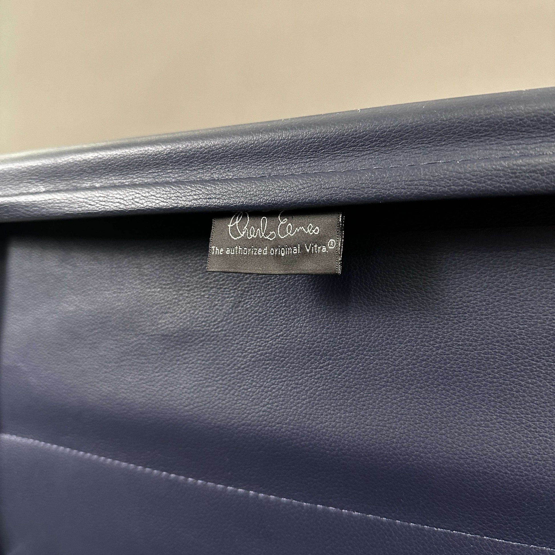 Blauer Vitra EA 219 Eames Alu Chair mit Lederbezug und Chromgestell close-up des Markenetiketts