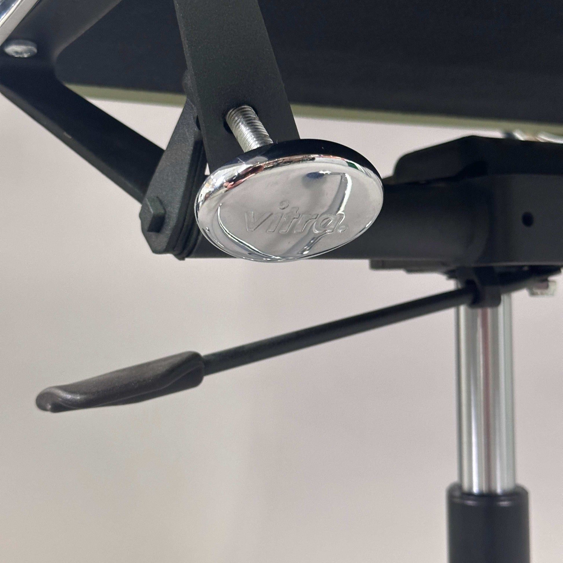 Detailaufnahme der verchromten Sitzhöhenverstellung des Vitra EA 219 Eames Alu Chair mit hellgrünem Lederbezug