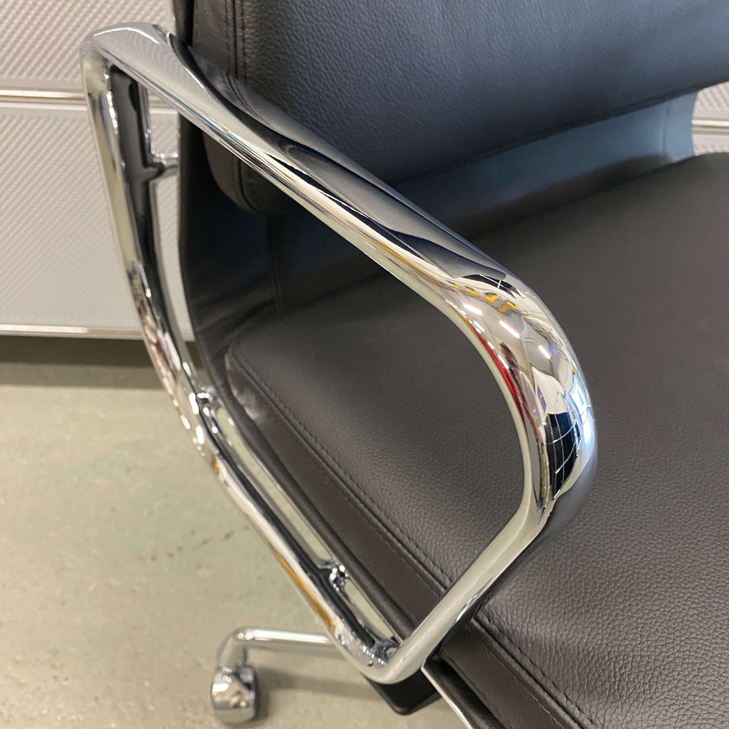 Close-up of black leather Vitra EA 219 office chair with chrome armrest and adjustable reclining mechanism