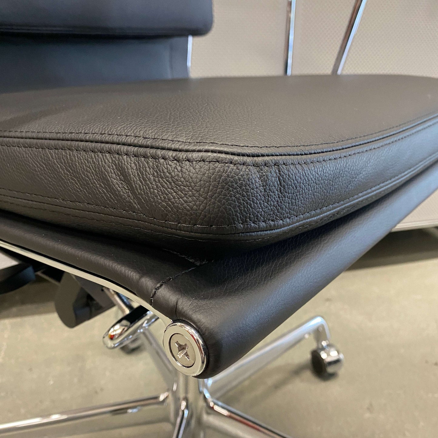 Close-up of Vitra EA 219 ergonomic office chair seat with black leather upholstery and chrome frame