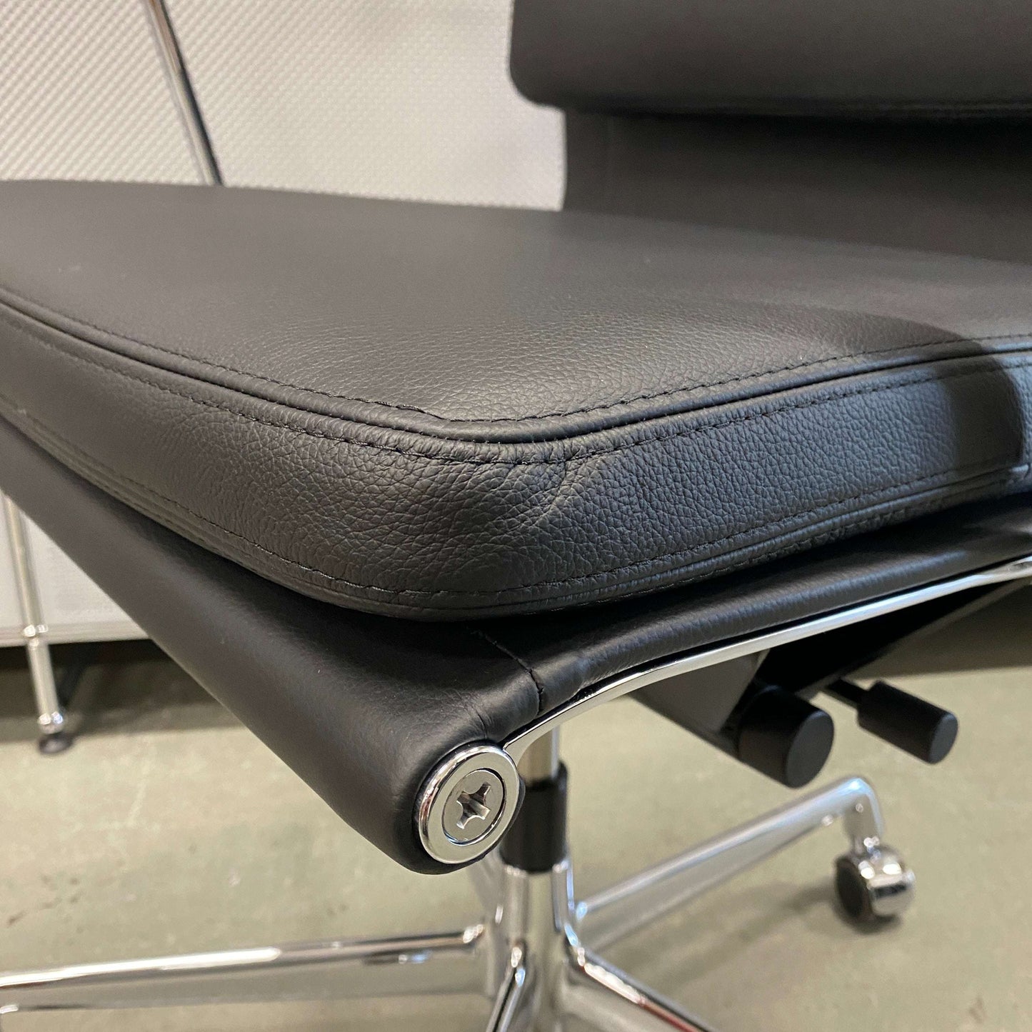 Close-up of Vitra EA 219 office chair in black leather with chrome frame and adjustable reclining mechanism.