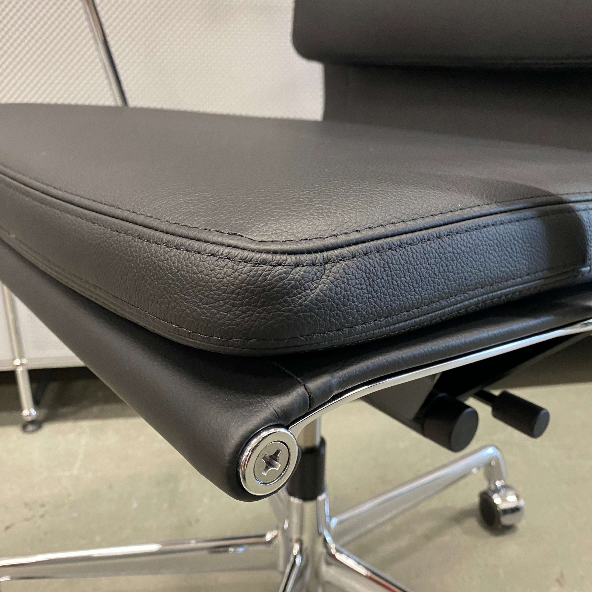 Close-up of Vitra EA 219 office chair in black leather with chrome frame and adjustable reclining mechanism.