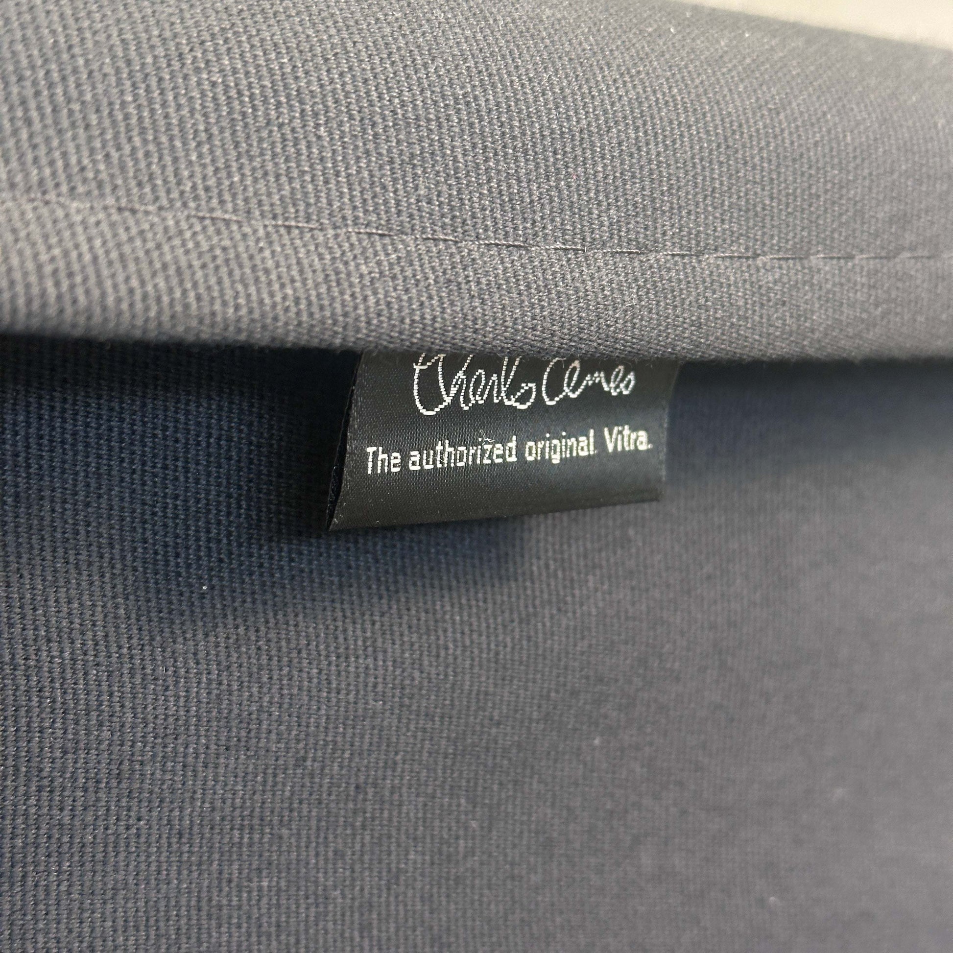 Nahaufnahme des schwarzen Stoffbezugs mit Vitra EA 219 Originaletikett am Stuhl