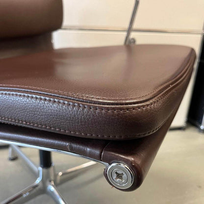 Close-up of brown Vitra EA Soft Pad Chair seat cushion with chrome swivel base