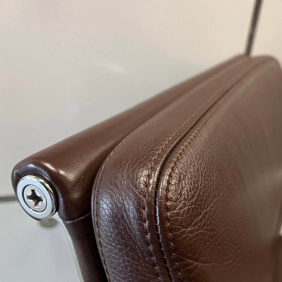 Close-up of the chestnut brown leather upholstery on the Vitra EA Soft Pad Chair with chrome frame