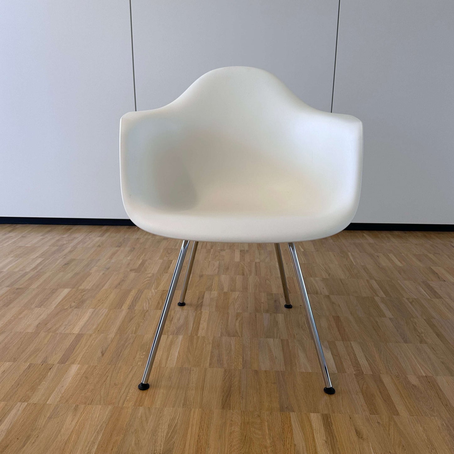 Vitra Eames Plastic Armchair weiß mit verchromtem Metallgestell auf Holzfußboden
