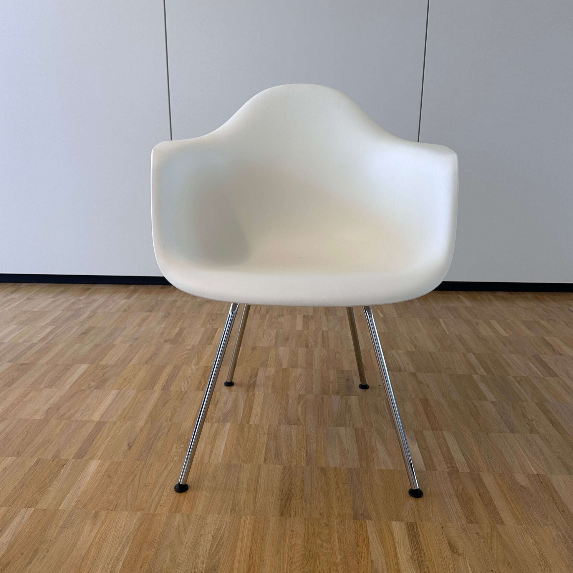 Vitra Eames Plastic Armchair weiß mit verchromtem Metallgestell auf Holzfußboden