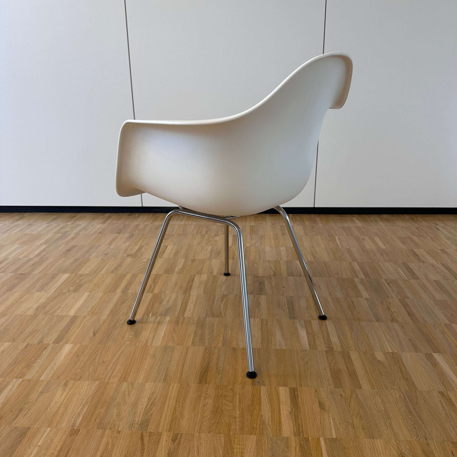 Vitra Eames Plastic Armchair weiß mit verchromtem Metallgestell auf Parkettboden, Rückansicht
