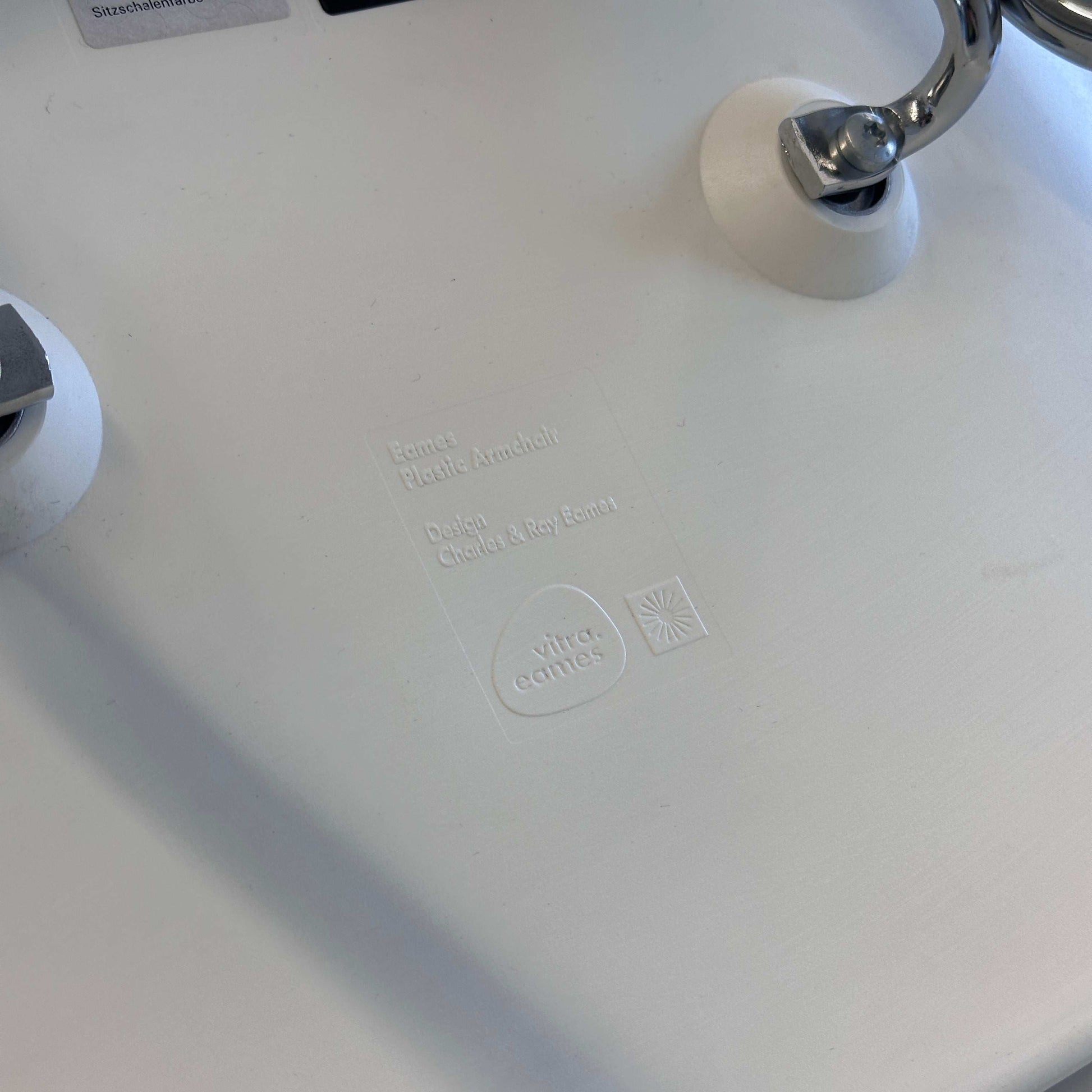 Vitra Eames Plastic Armchair Sitzschale PE weiß mit verchromtem Metallgestell Nahaufnahme Logo und Designprägung
