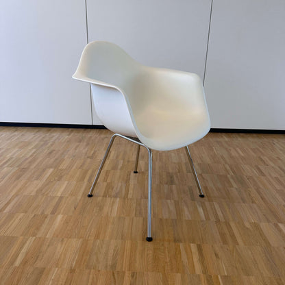 Vitra Eames Plastic Armchair weiß mit weißer PE-Sitzschale und verchromtem Metallgestell auf Holzboden vor weißer Wand