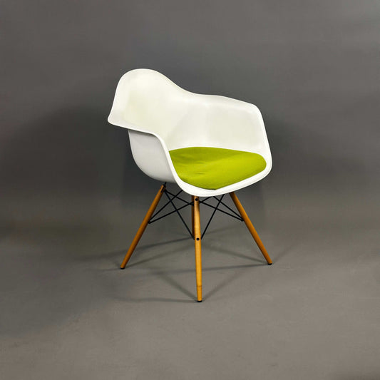 Vitra Eames Plastic Armchair weiß mit grünem Polster und Holzgestell mit Metallverstrebungen