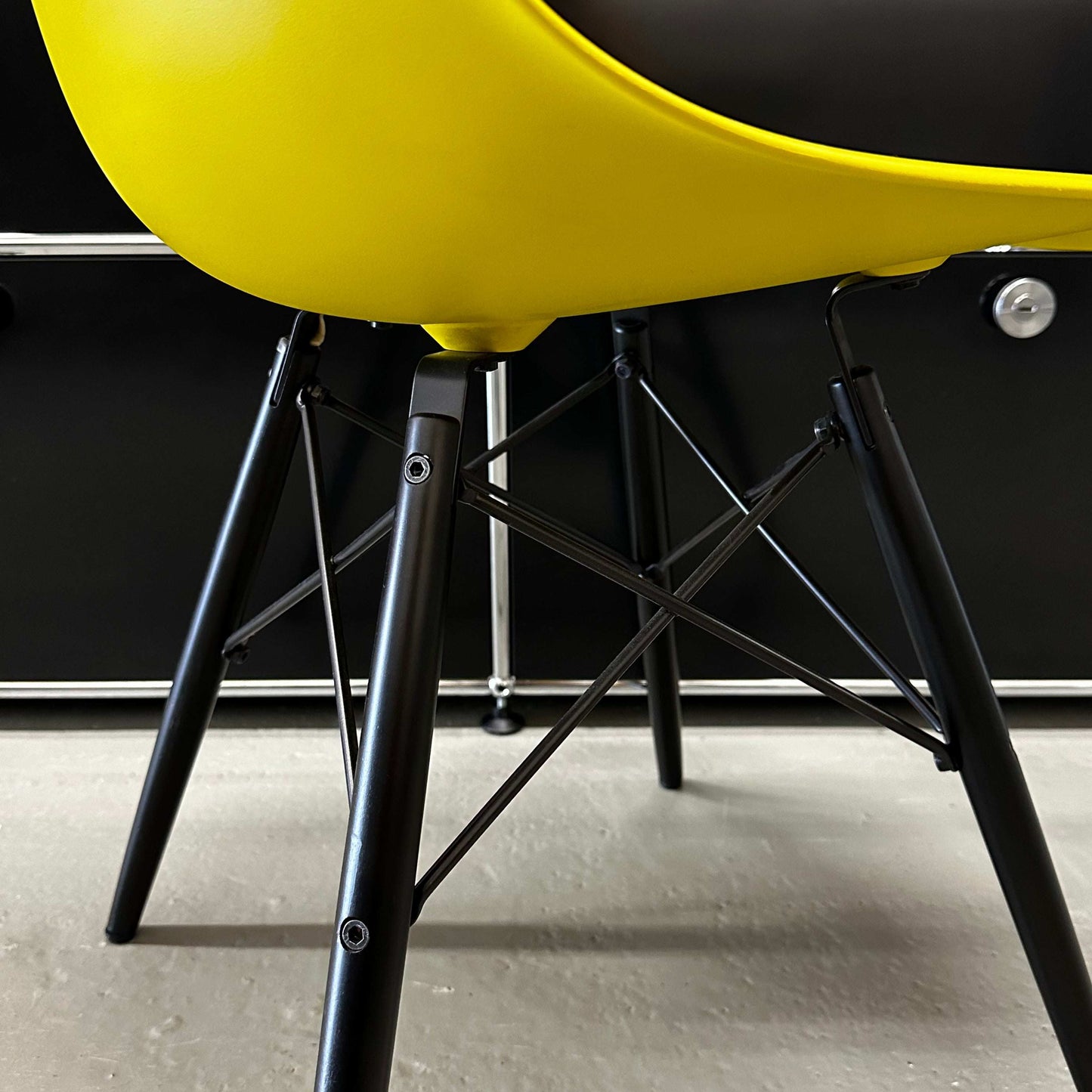 Close-up of Vitra Eames Plastic Sidechair with mustard yellow plastic seat and black wooden legs