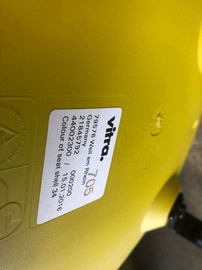 Close-up of mustard yellow Vitra Eames Plastic Sidechair seat with black wooden base label