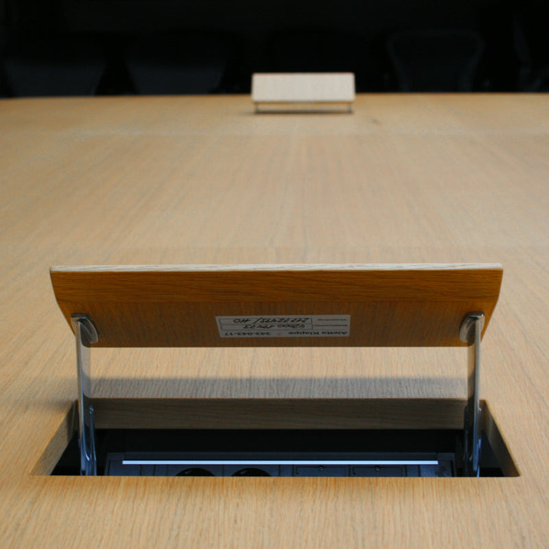 Vitra Eames Segmented Table, large oak veneer conference table with open power outlet.