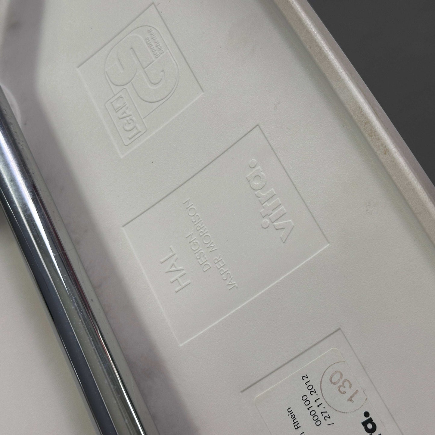 Vitra HAL Schalenstuhl weiße Kunststoffsitzschale mit verchromtem Metallgestell Detailansicht Herstellerlogo und Modellprägung unter dem Sitz