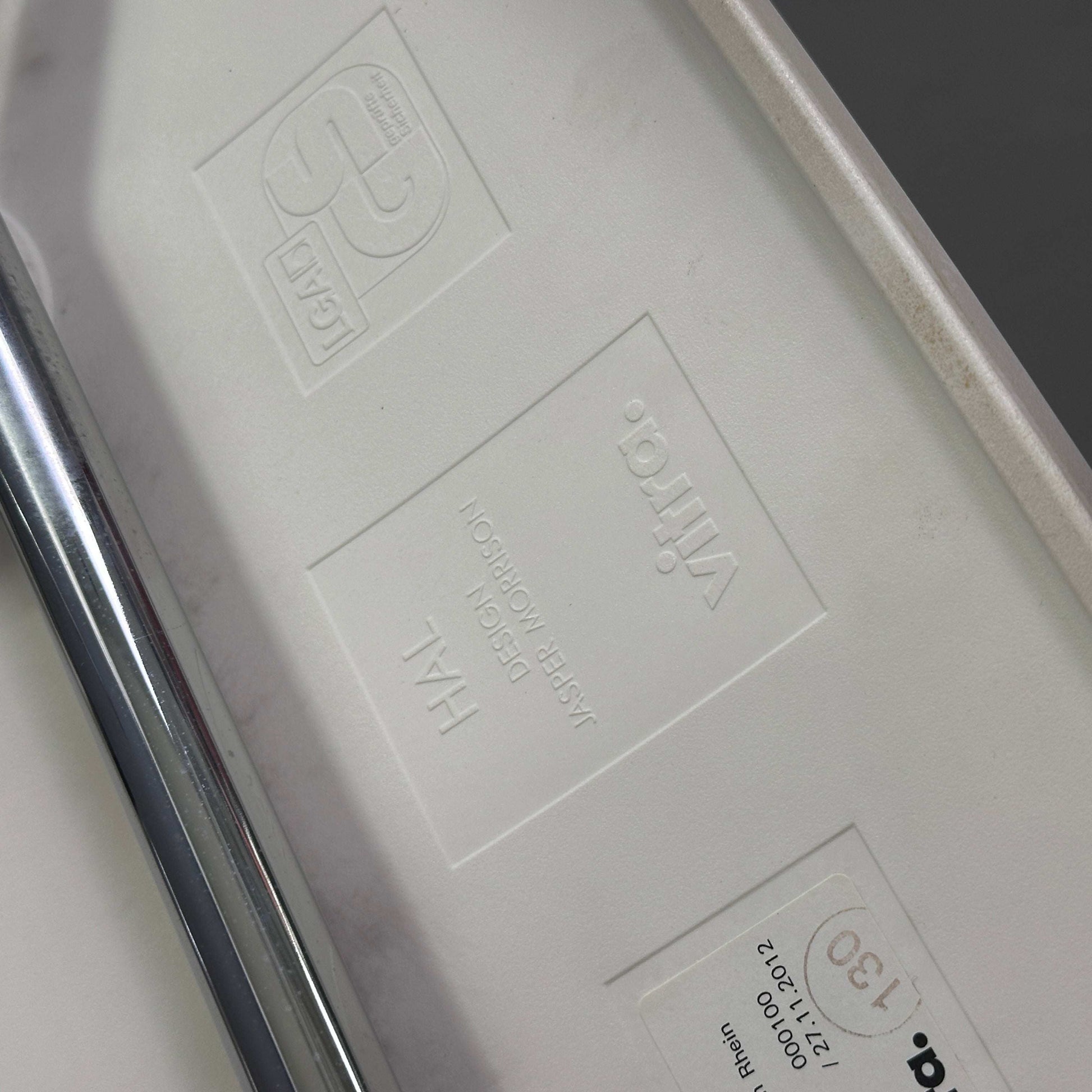 Vitra HAL Schalenstuhl weiße Kunststoffsitzschale mit verchromtem Metallgestell Detailansicht Herstellerlogo und Modellprägung unter dem Sitz