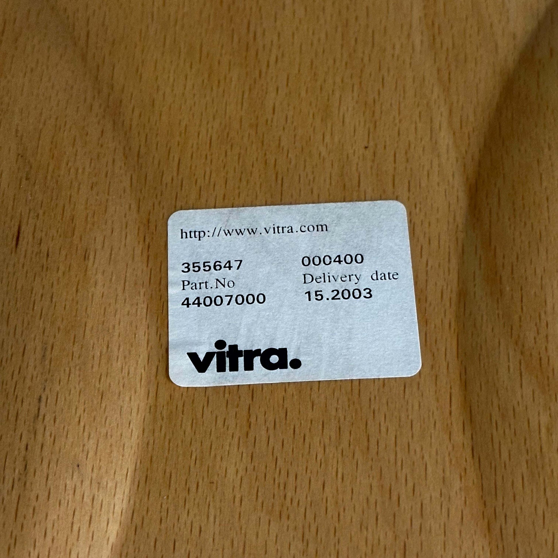 Label with Vitra logo on oak wood surface for Vitra Holz Stapelstuhl chair shipped in 2003