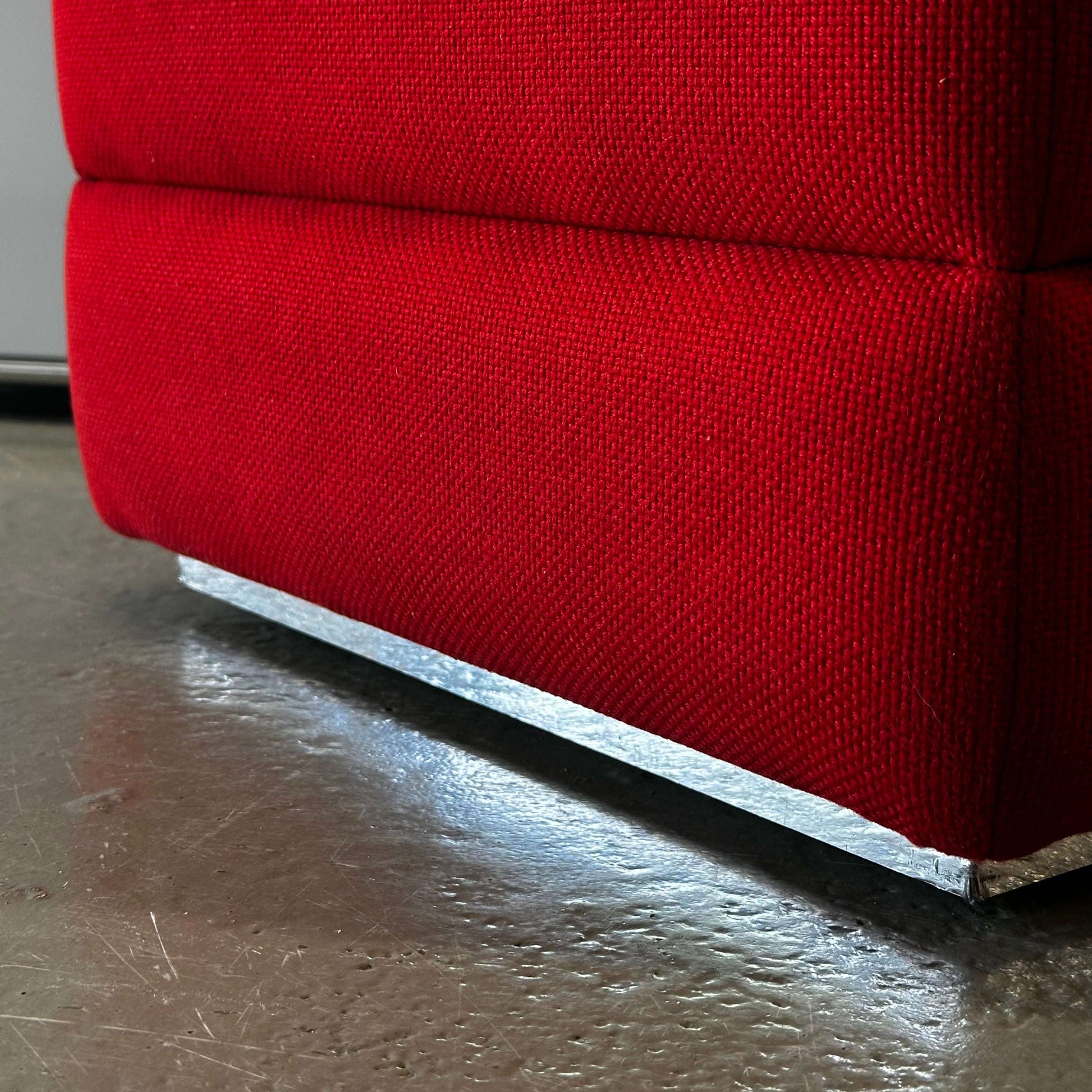 Close-up of red Vitra Hopsak Hocker fabric and metal base on floor