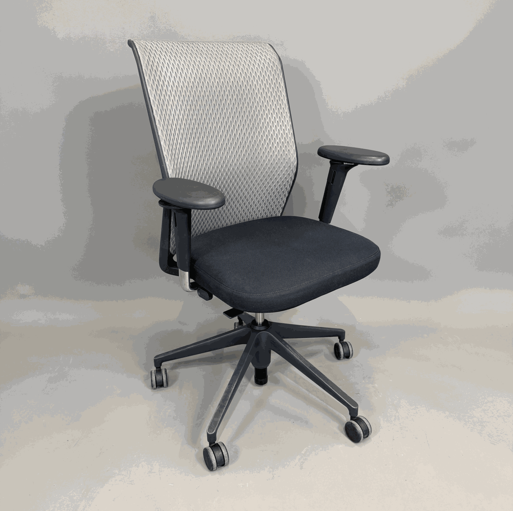 Vitra ID Mesh office chair with black seat, gray mesh backrest, and adjustable 3D armrests on wheels