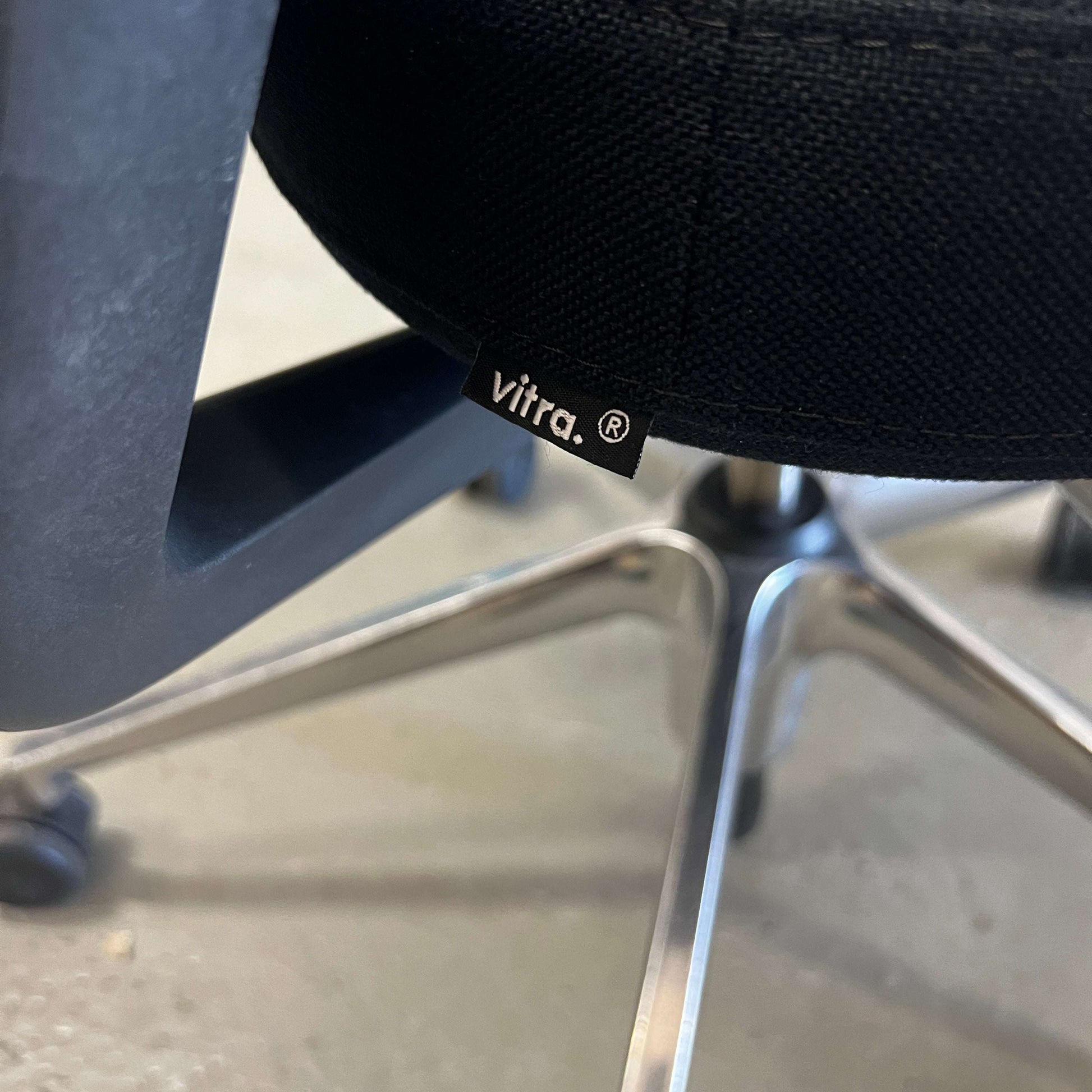 Close-up of black Vitra ID Mesh office chair with aluminum armrests and fine mesh material showing adjustable features and universal wheels