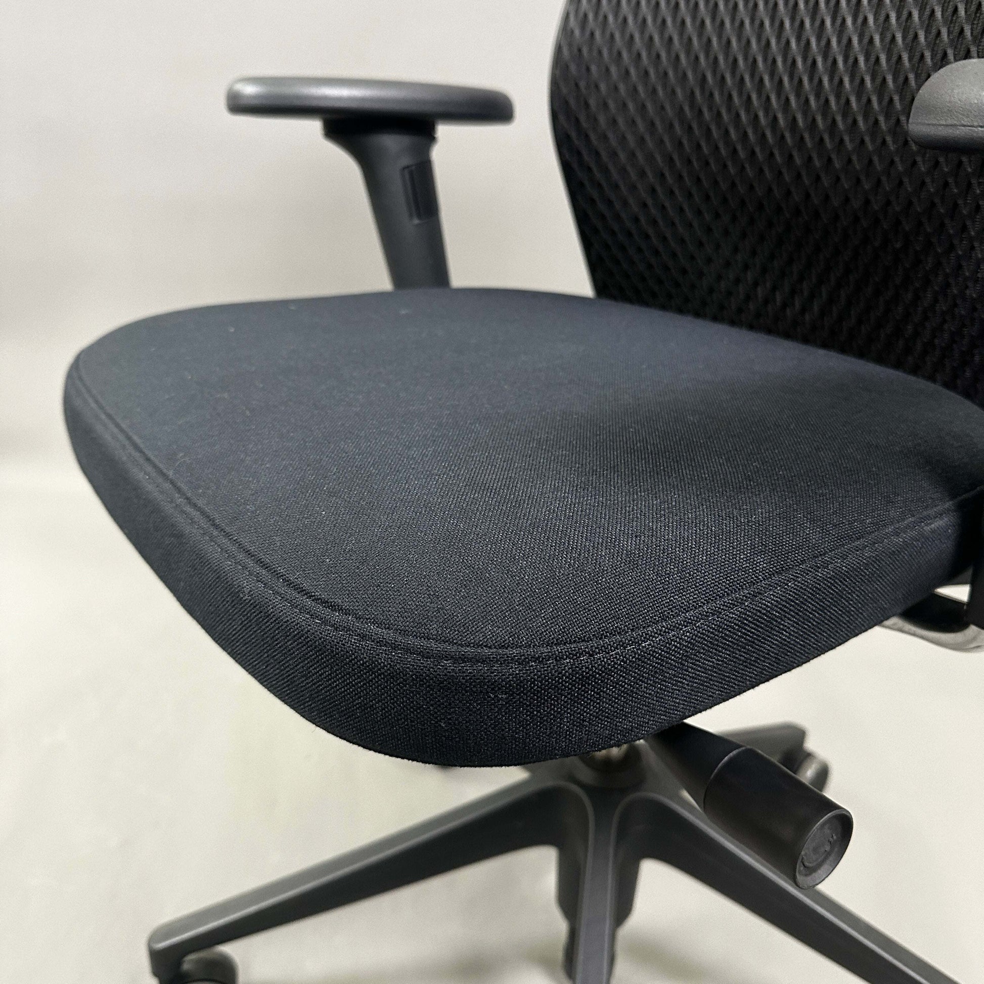 Close-up of Vitra ID Mesh black office chair seat and armrest with diamond mesh backrest and adjustable features