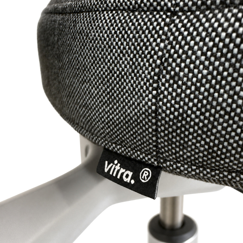 Detailansicht des Vitra ID Trim L Bürostuhls mit grau-blauem Stoffbezug und Vitra-Logo-Label.