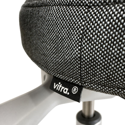 Detailansicht des Vitra ID Trim L Bürostuhls mit grau-blauem Stoffbezug und Vitra-Logo-Label.