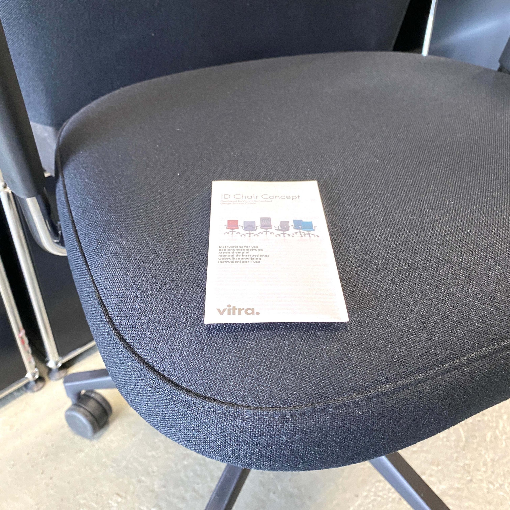 Close-up of black fabric seat of Vitra ID Trim L office chair with adjustable ergonomic features and black leather headrest
