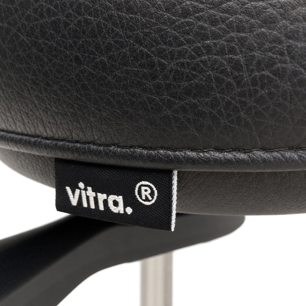 Schwarzer Vitra ID Trim Bürostuhl mit hochwertigem Lederbezug und markantem Vitra-Logo-Label an der Sitzkante.