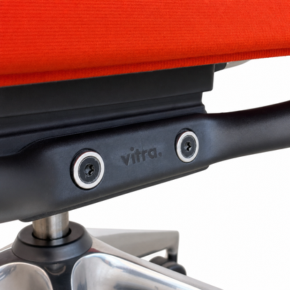 Vitra ID Trim Bürostuhl mit orange-rotem Stoffbezug, schwarzer Armlehnenhalterung und poliertem Aluminiumfuß.