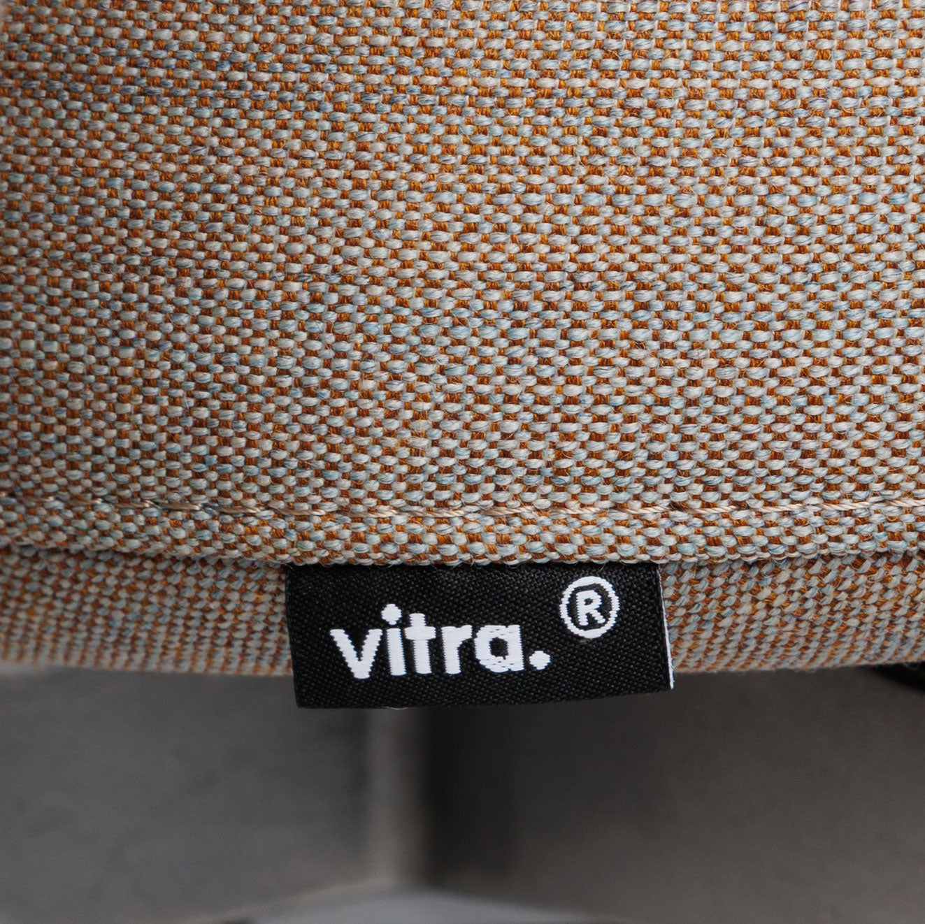 Nahaufnahme des Vitra ID Trim Bürostuhls mit grau/braunem Stoffbezug und Vitra-Label.