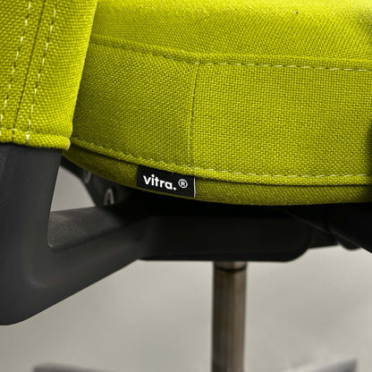 Nahaufnahme des grünen Vitra ID Trim Bürostuhls mit Stoffbezug und Chrom-Fußkreuz