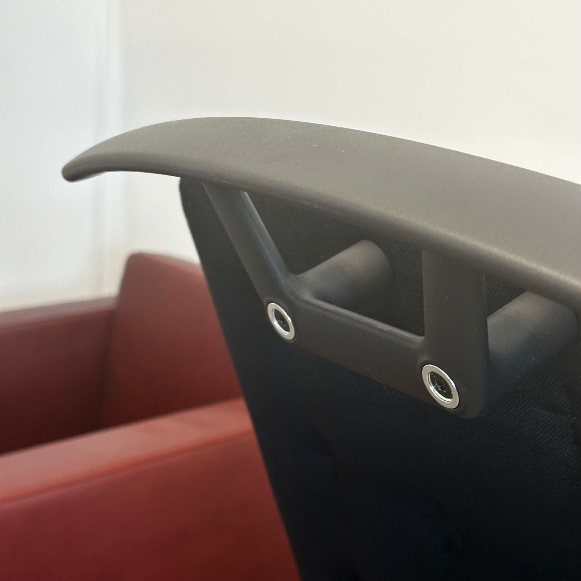 Close-up of black Vitra ID Trim office chair armrest with adjustable height mechanism and lumbar support features
