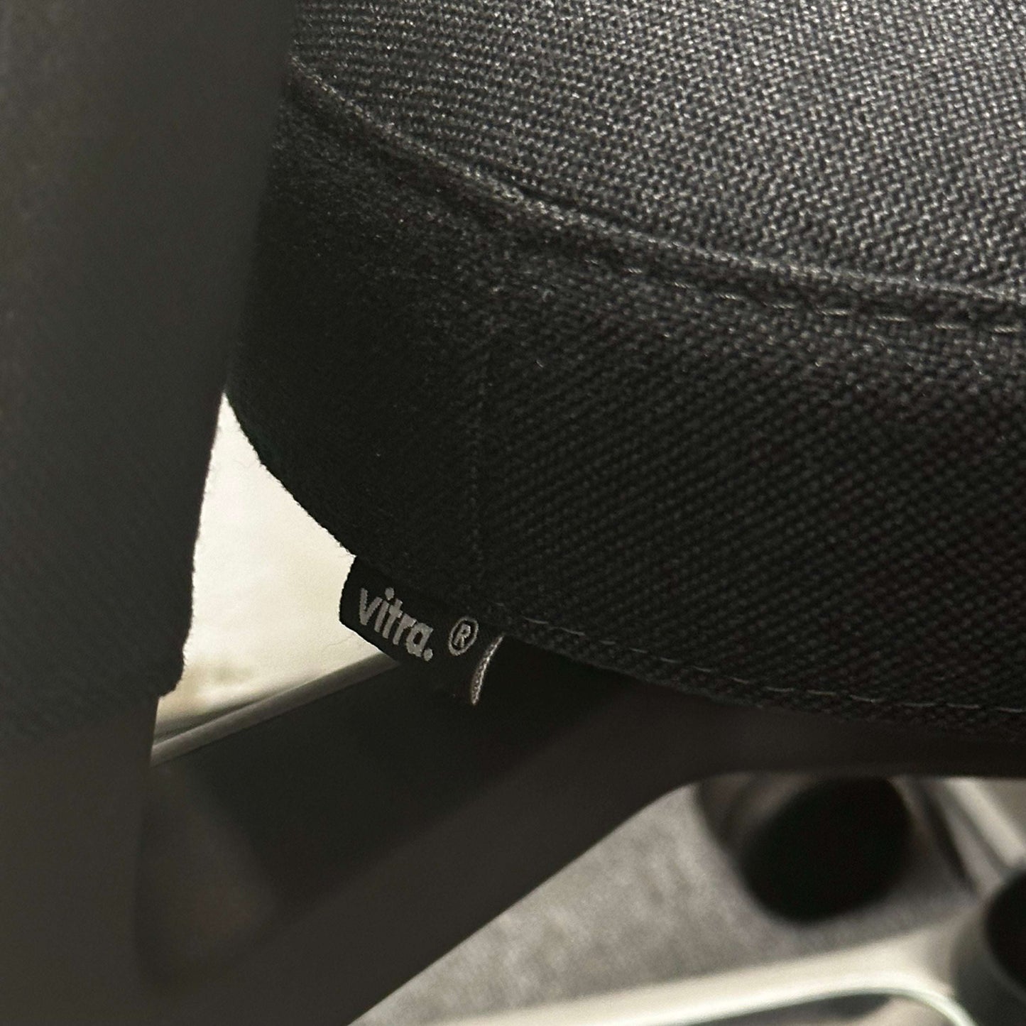 Close-up of black Vitra ID Trim office chair fabric with Vitra logo tag and metal frame details