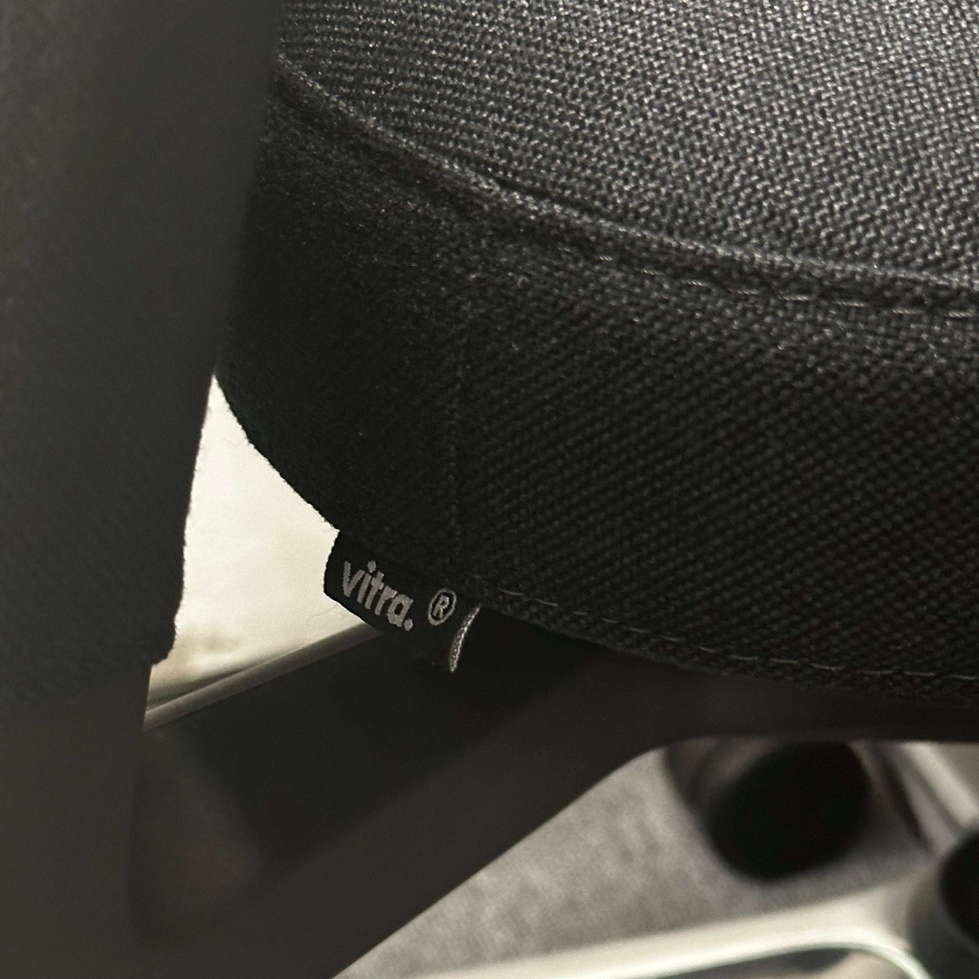 Close-up of black Vitra ID Trim office chair fabric with Vitra logo tag and metal frame details