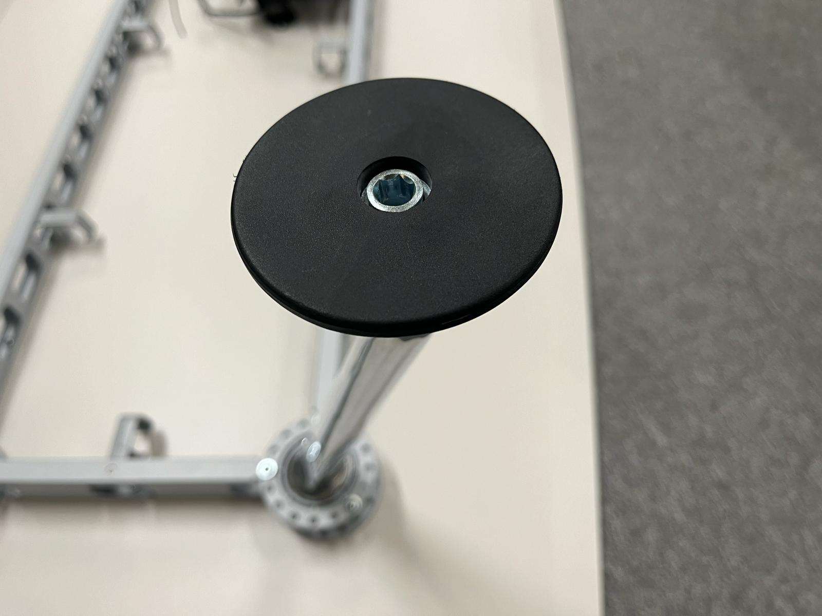 Close-up of Vitra Medamorph meeting table leg with adjustable black footrest on grey carpet background