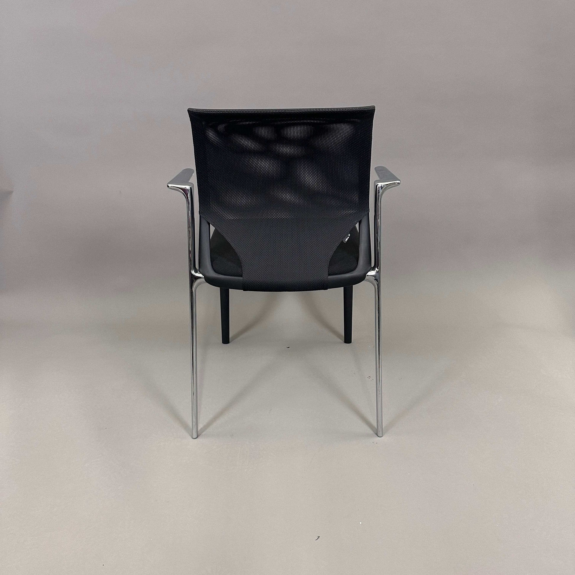 Vitra Medaslim chair with black mesh backrest, padded black seat, and chrome armrests and frame viewed from the back