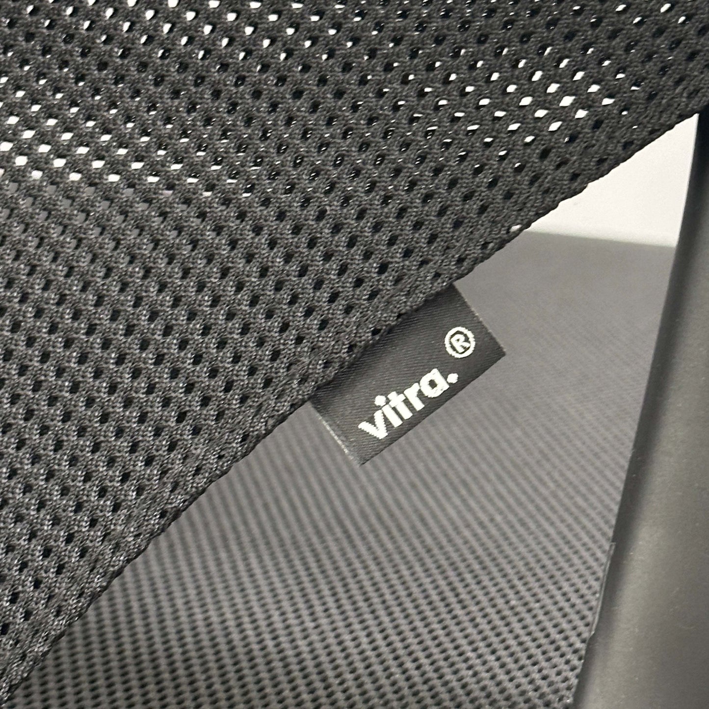 Close-up of Vitra Medaslim office chair featuring black mesh backrest and cushioned seat with Vitra label.