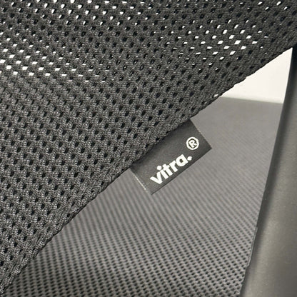 Close-up of Vitra Medaslim office chair featuring black mesh backrest and cushioned seat with Vitra label.