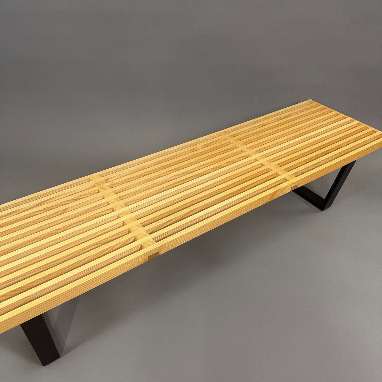 Vitra Nelson Bench aus braunem Eschenholz mit schlanker Lattenkonstruktion und schwarzem Metallgestell