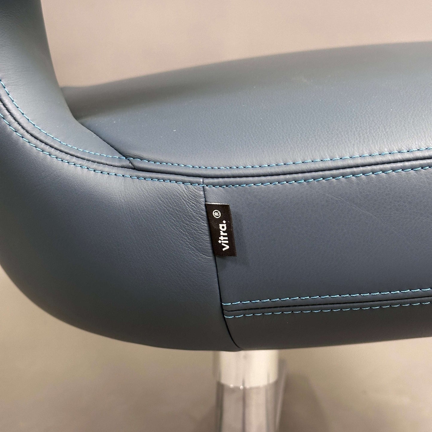 Detailaufnahme des blauen Vitra Petit Repos Sessels aus Premiumleder mit blauen Ziernähten und verchromtem Stahlgestell.