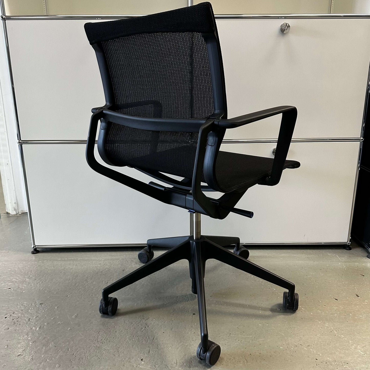 Black Vitra Physix ergonomic office chair with mesh back and adjustable armrests on wheels