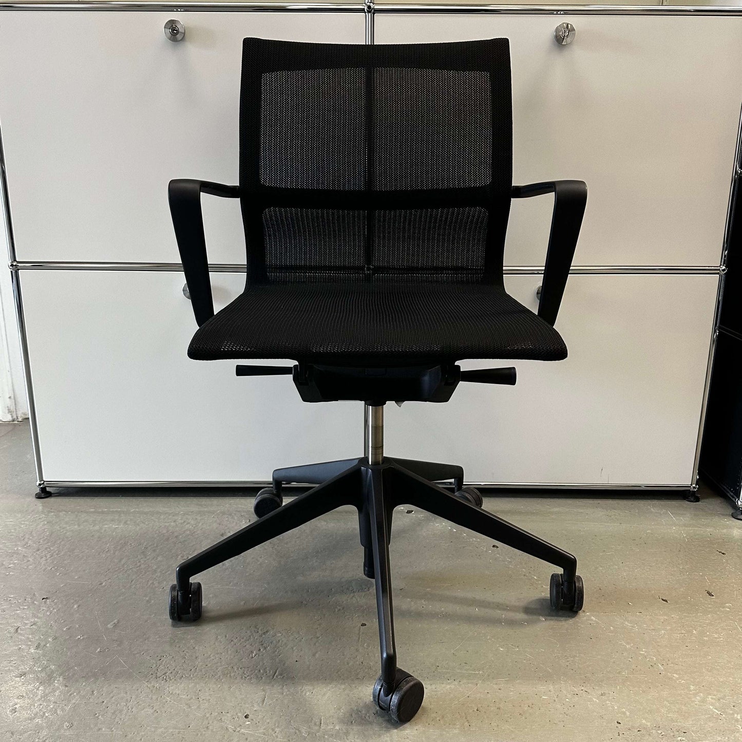 Black Vitra Physix ergonomic office chair with mesh back and adjustable armrests on caster wheels