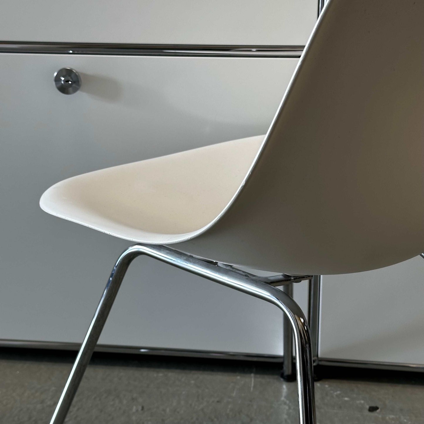 White Vitra Plastic Side Chair with minimalist plastic seat and chrome legs in modern interior setting