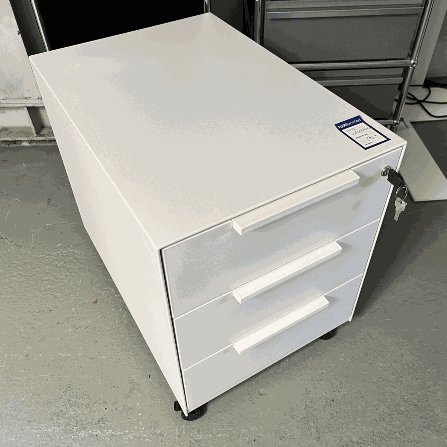 White Vitra Rollcontainer with three drawers, metal body and plastic fronts, dimensions 42x54x61 cm, on casters with key lock.
