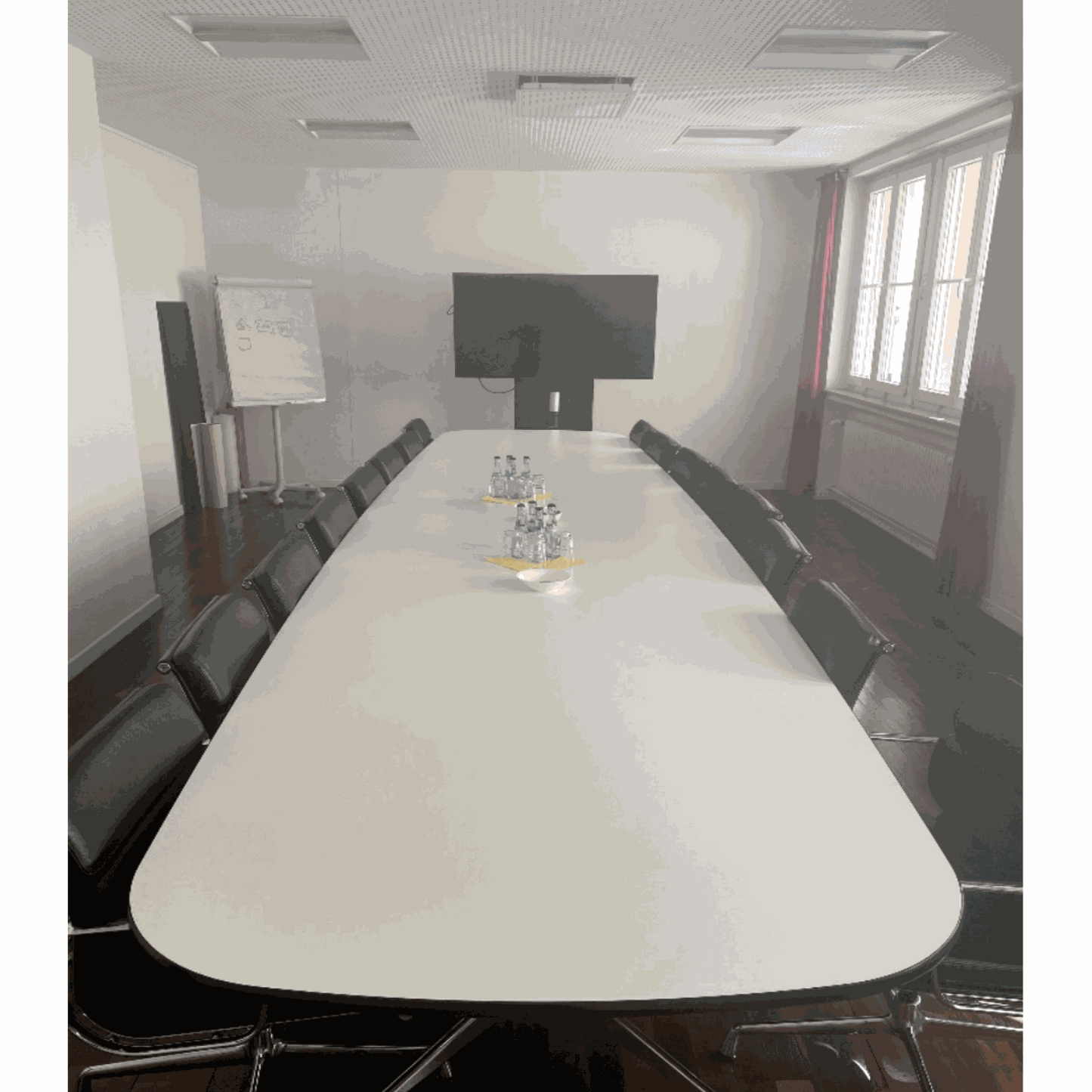 Moderner Vitra Segmented Tisch 560x136cm im Besprechungsraum mit schwarzen Stühlen und großem Bildschirm