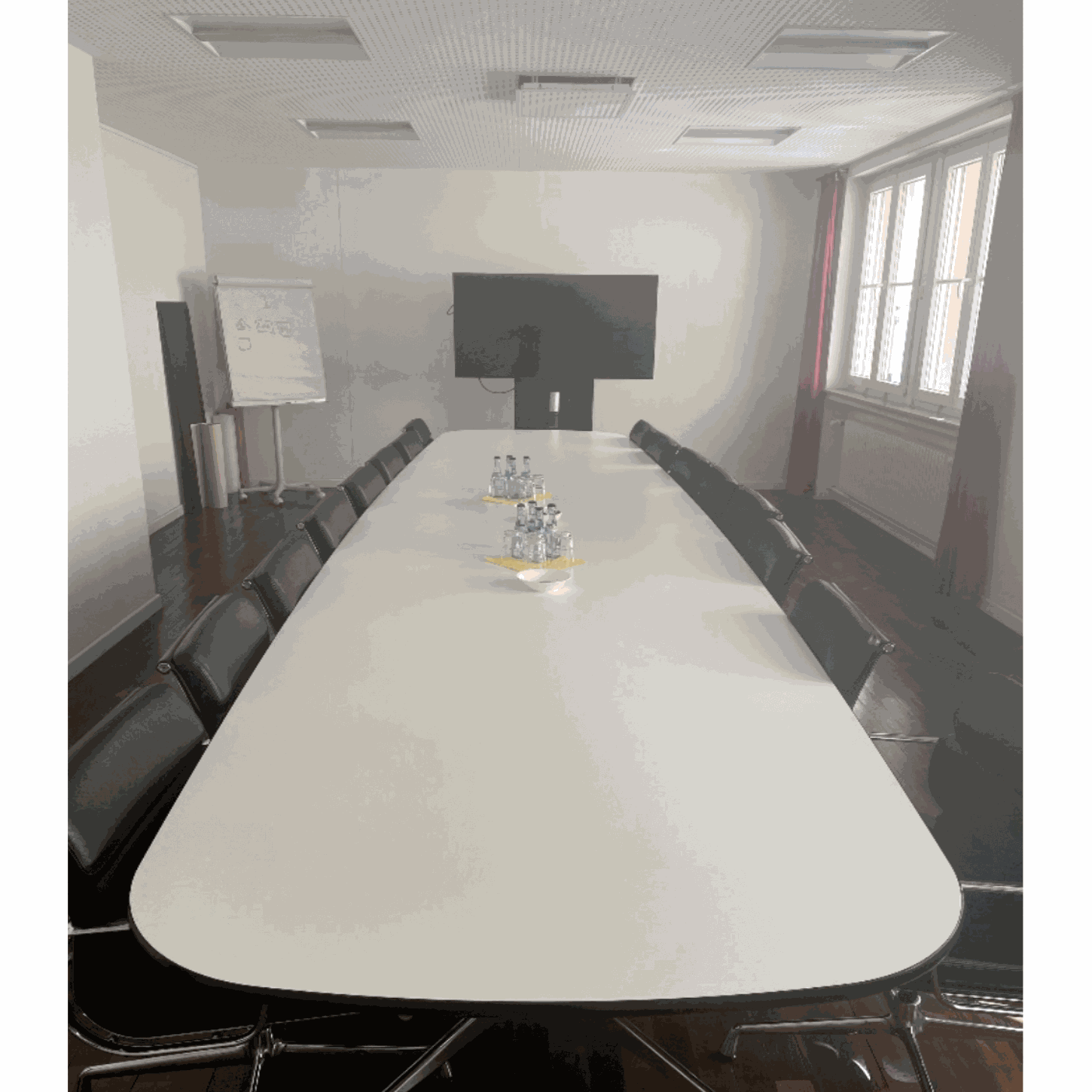 Moderner Vitra Segmented Tisch 560x136cm im Besprechungsraum mit schwarzen Stühlen und großem Bildschirm
